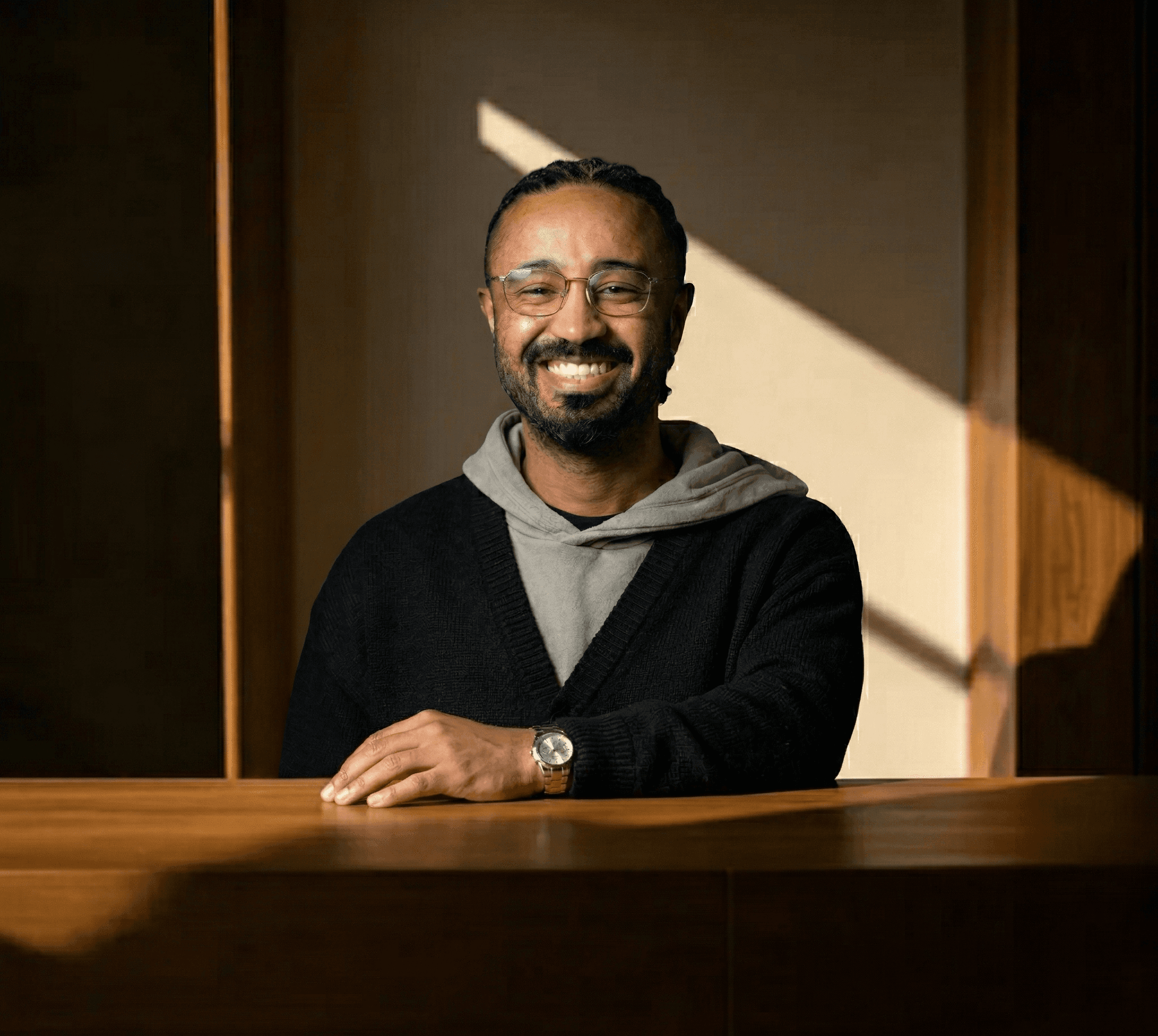 Portrait of a smiling recruiter seated behind a wooden desk in a softly lit office